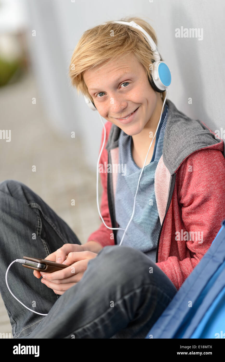 Glücklich Teenager-Studentin anhören von Musik tragen Kopfhörer, draußen zu sitzen Stockfoto