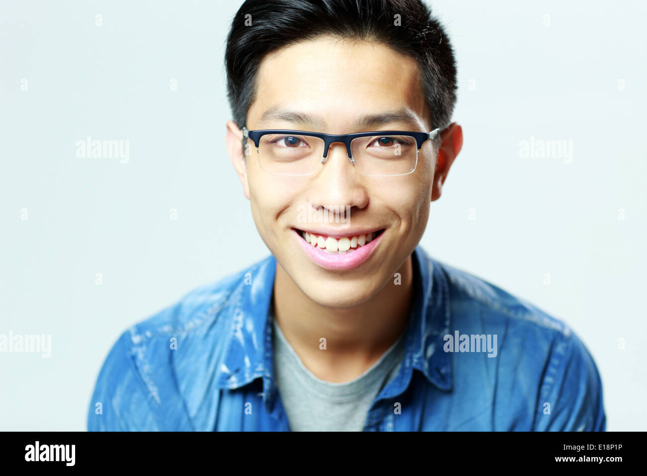 Porträt eines lächelnden jungen Mannes in Gläsern auf grauem Hintergrund Stockfoto