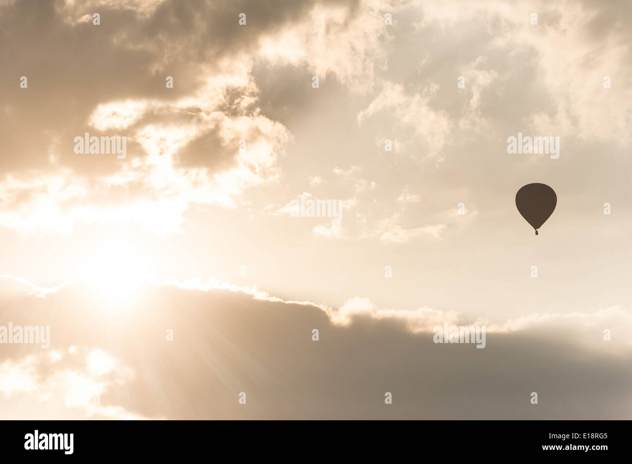 Erstaunliche Farben des Sonnenaufgangs mit Sonnenstrahlen über Wolken und Heißluft-Ballon-silhouette Stockfoto
