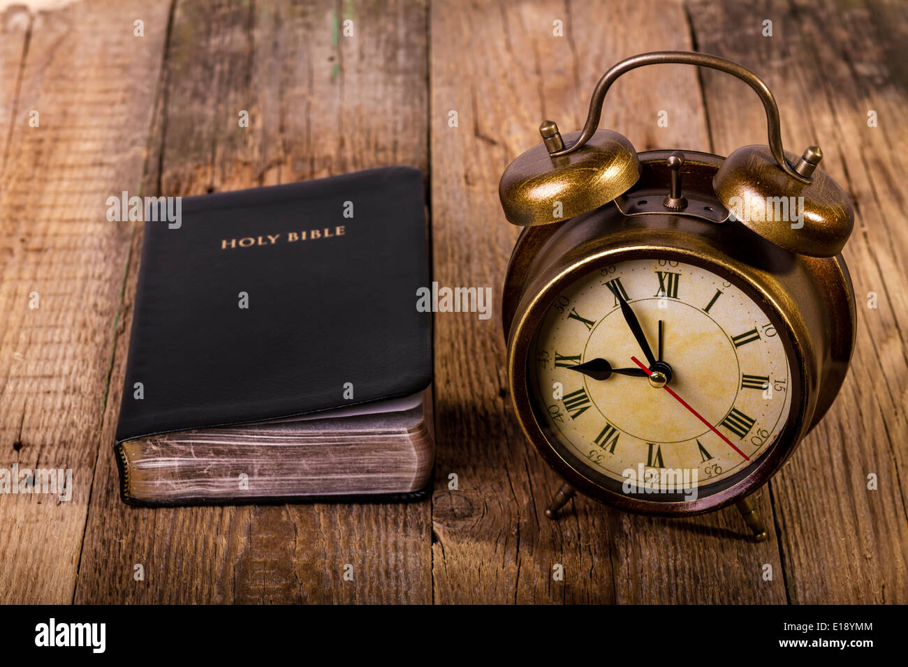 Bibel mit Uhr auf Holz. Uhr im Mittelpunkt. Stockfoto