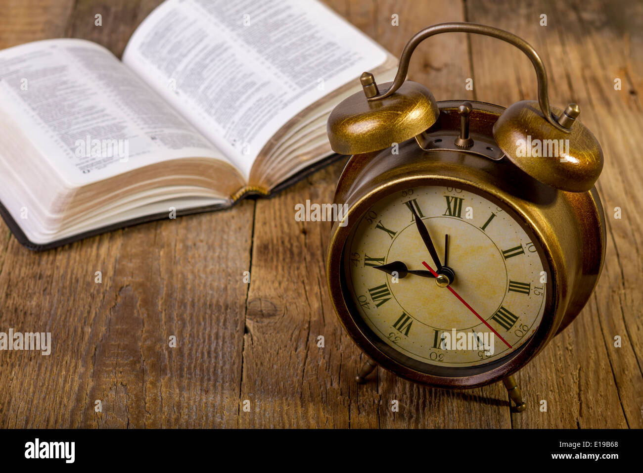 Offene Bibel mit Uhr auf Holz Stockfoto