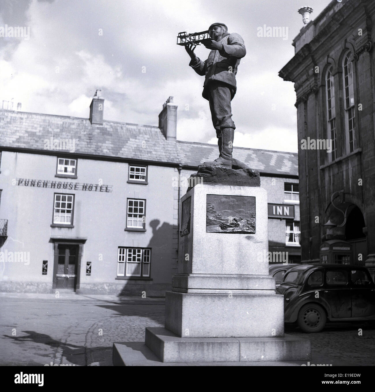 1950er Jahre, historische Statue von Charles Rolls, dem Luftfahrtpionier, mit einem Doppeldecker vor der Shire Hall, Agincourt Square, Monmouth, Wales, Großbritannien. Rolls, der Mitbegründer von Rolls Royce, dessen Familienanwesen im County lag, starb 1910, als er einen Wright Flyer flog, einen Doppeldecker in der Nähe von Bournemouth, England. Stockfoto