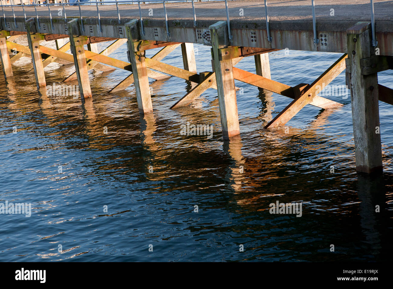 Die Beinstützen von einem Steg im Sonnenlicht eintretende Meerwasser gebadet. Stockfoto