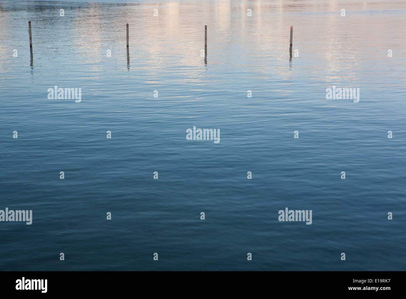 Reflexionen von den bewölkten Himmel im Meer, sind vier Buhnen aus dem Wasser ragte. Stockfoto