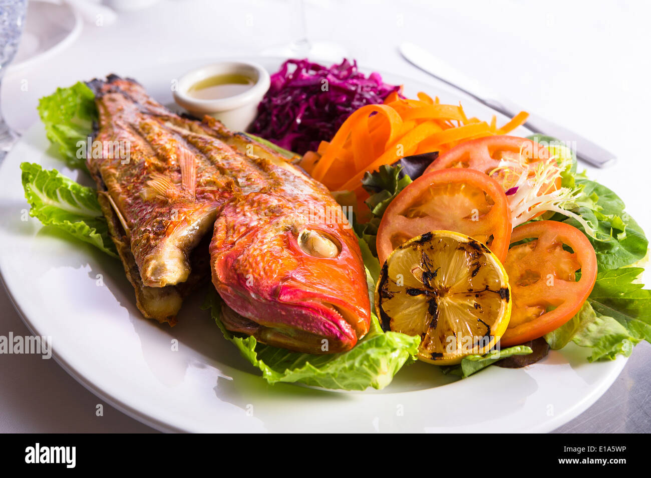 Komplettes warmes sündhaft schönen Tilapia Fisch serviert in einem Teller mit Gemüse und Fisch-sauce Stockfoto