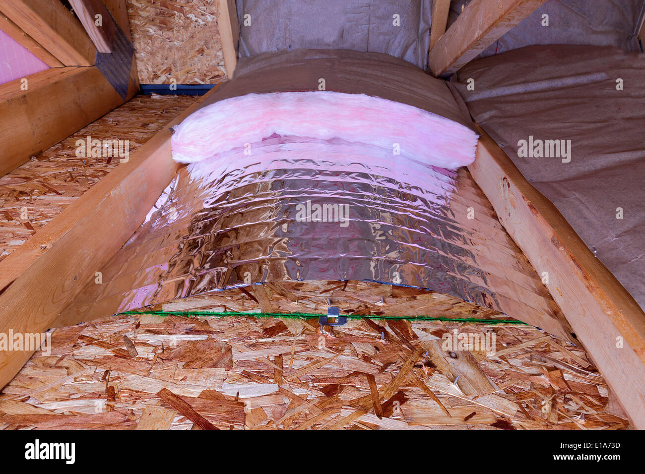 Isolierung des Dachbodens mit Fiberglas kalt Barriere und reflektierende Hitze Barriere als Trennwand zwischen den Dachboden Balken, Arbeit Stockfoto