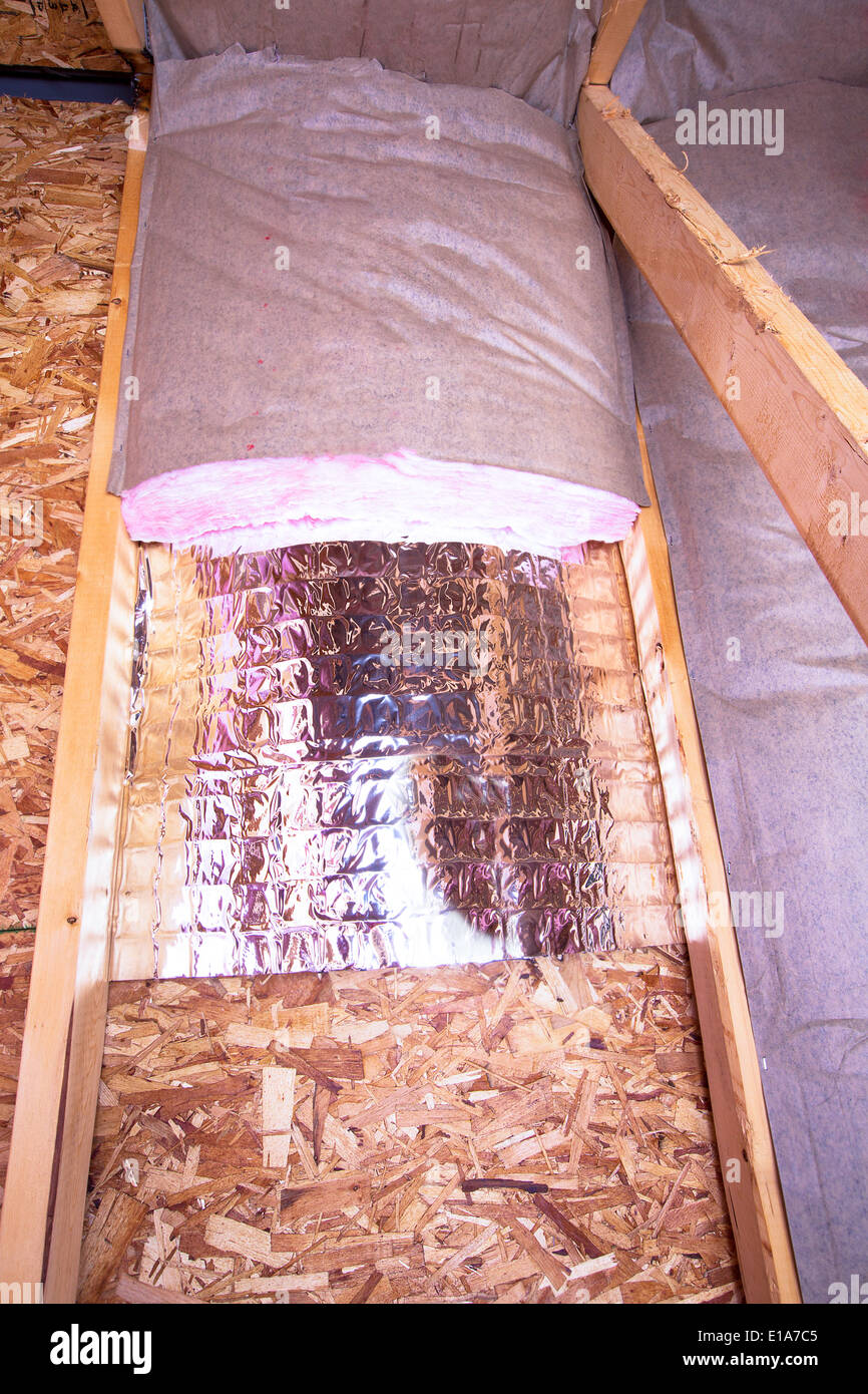 Isolierung des Dachbodens mit Fiberglas kalt Barriere und reflektierende Hitze Barriere zwischen den Dachboden-Balken, läuft die Arbeit Stockfoto