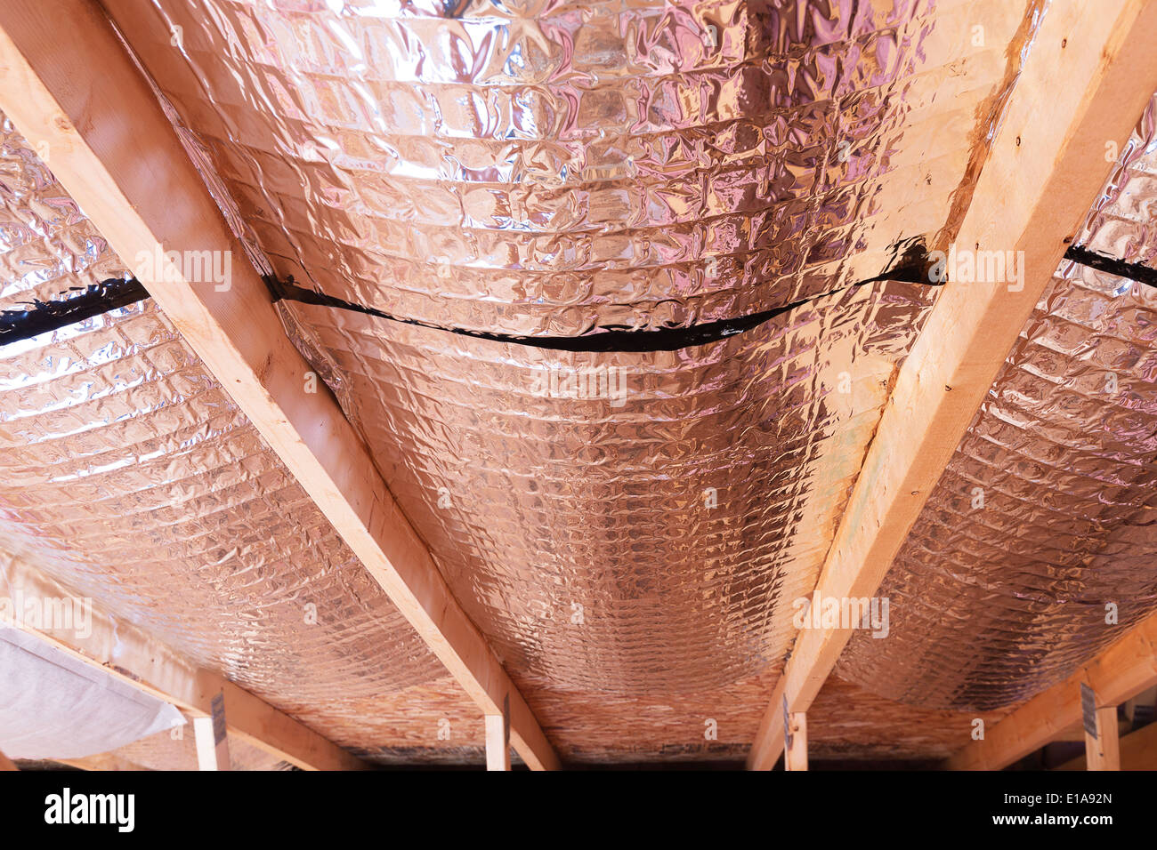 Isolierung des Dachbodens mit Fiberglas kalt Barriere und reflektierende Hitze Barriere als Trennwand zwischen den Dachboden Balken zu erhöhen Stockfoto