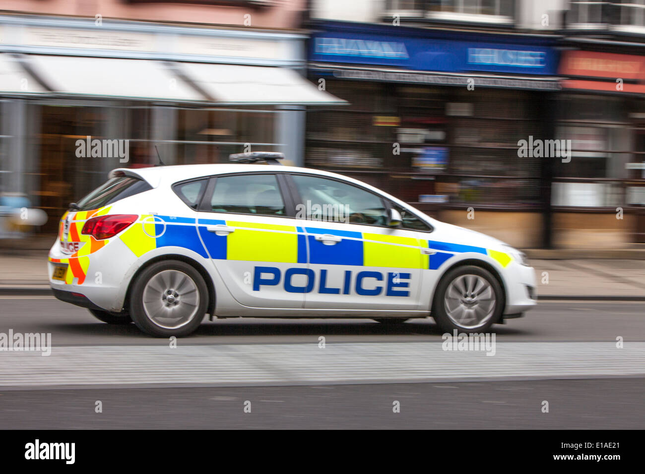 Polizeiauto, das durch eine Hauptstrasse der Stadt, England, Großbritannien, fährt Stockfoto