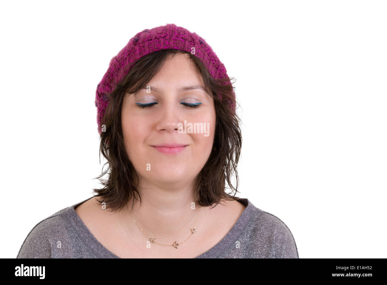 Frau trägt einen lila Strickmütze mit einem Ausdruck der reinen Glückseligkeit lächelnd in Ekstase mit ihren Augen geschlossen isoliert auf weiss Stockfoto