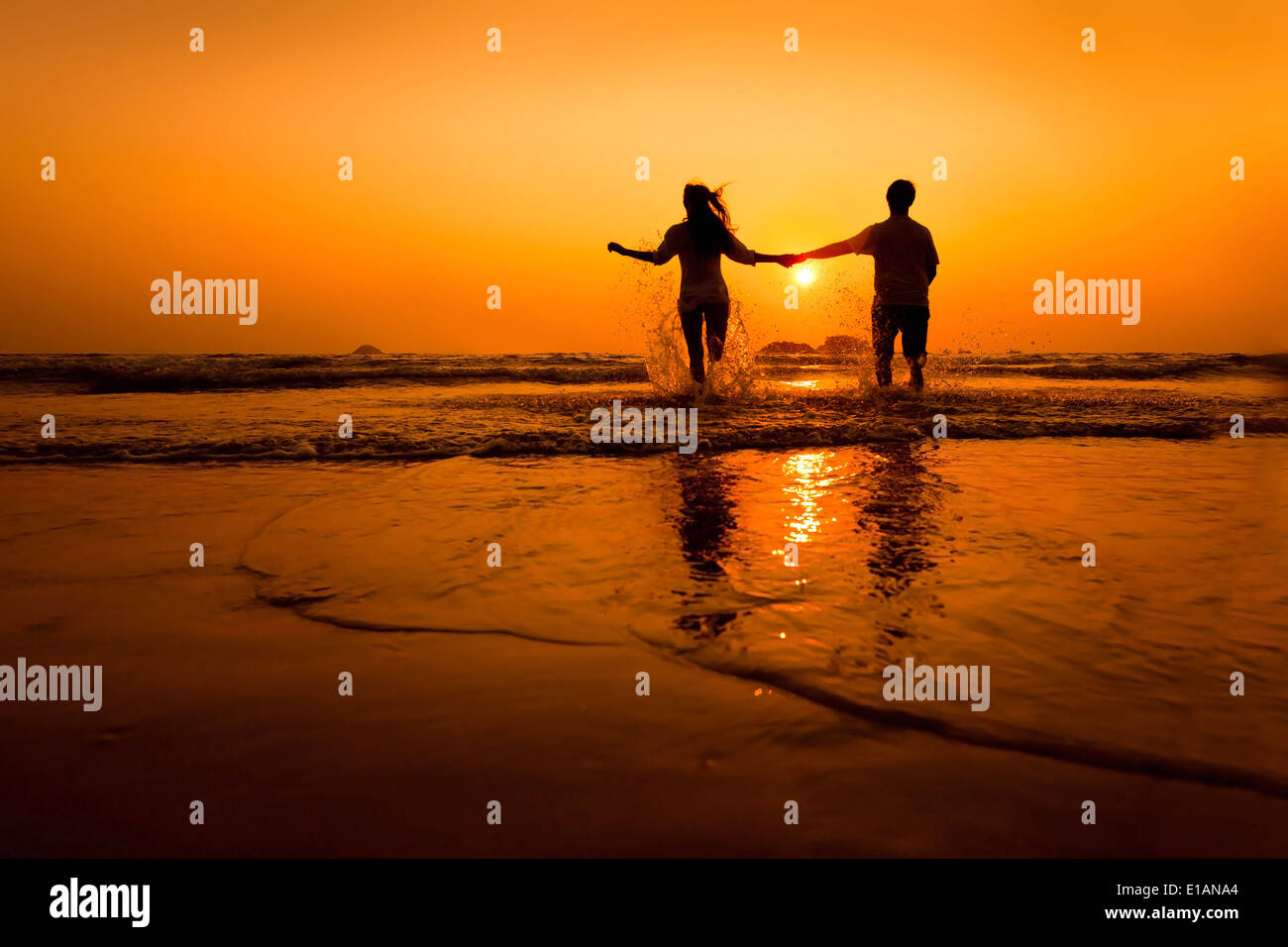 Silhouetten von paar läuft bis zum Meer am Strand bei Sonnenuntergang Stockfoto