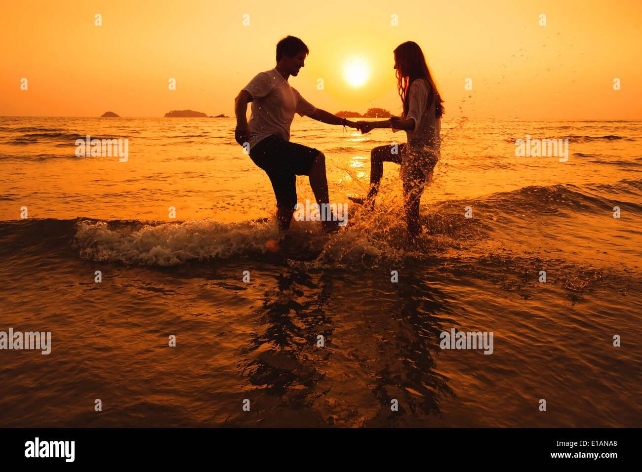 Paare, die Spaß im Meer bei Sonnenuntergang Strand Stockfoto