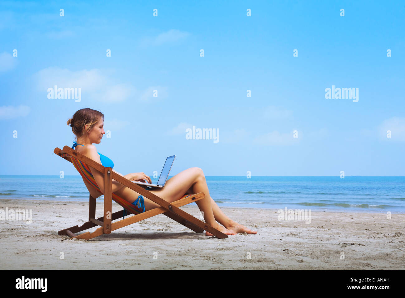 Frau im Bikini am Strand sitzen mit laptop Stockfoto
