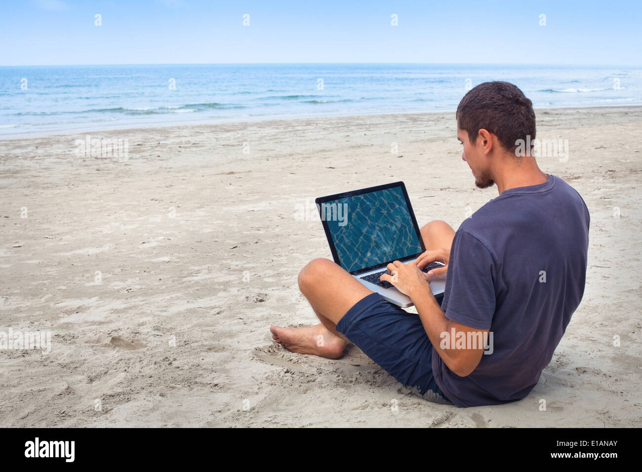 Mann mit Computer mit WLAN am Strand Stockfoto