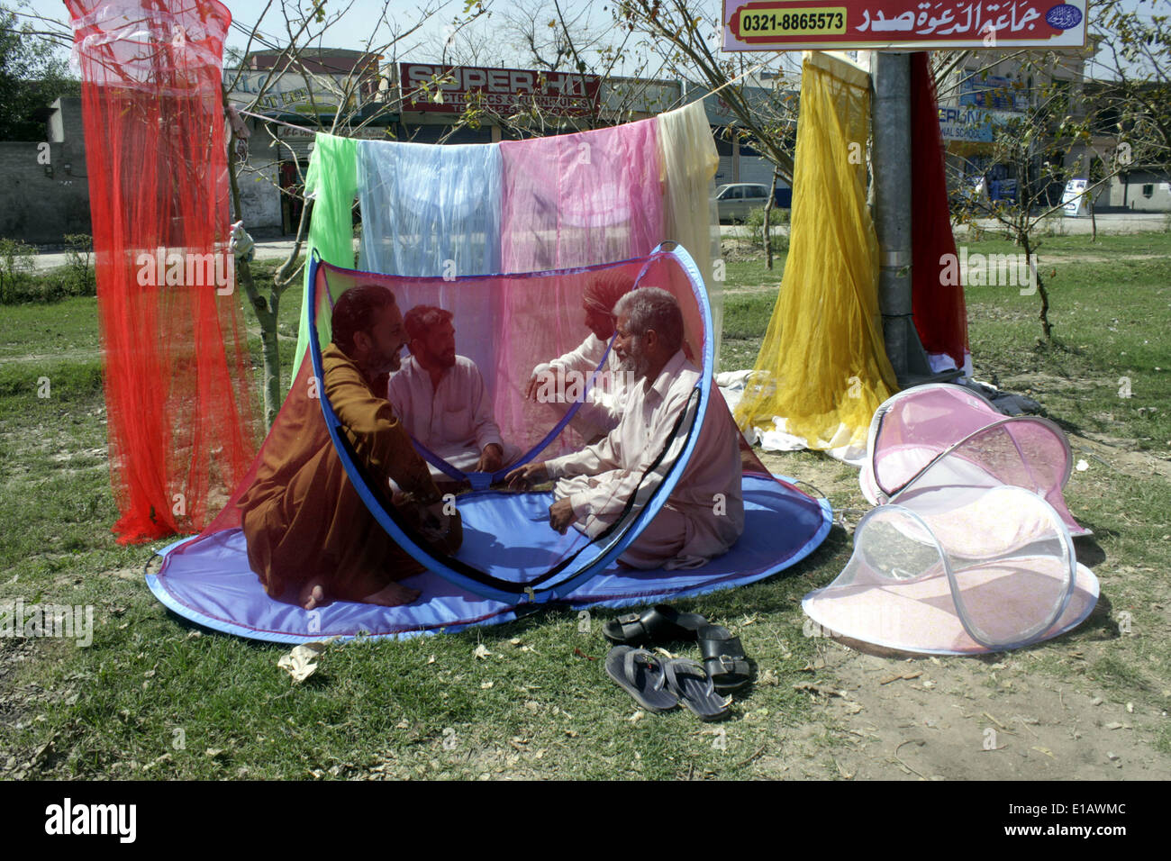 Lahore, Pakistan. 29. Mai 2014. Pakistanische Kreditoren chatten, wie sie im Inneren ein Moskitonetz in Lahore, östlichen Pakistan, 29. Mai 2014 sitzen. Medizinische Experten geraten pakistanische Bürger, spezielle vorbeugende Maßnahmen zum Schutz von Dengue-Virus tragen. Bildnachweis: Jamil Ahmed/Xinhua/Alamy Live-Nachrichten Stockfoto