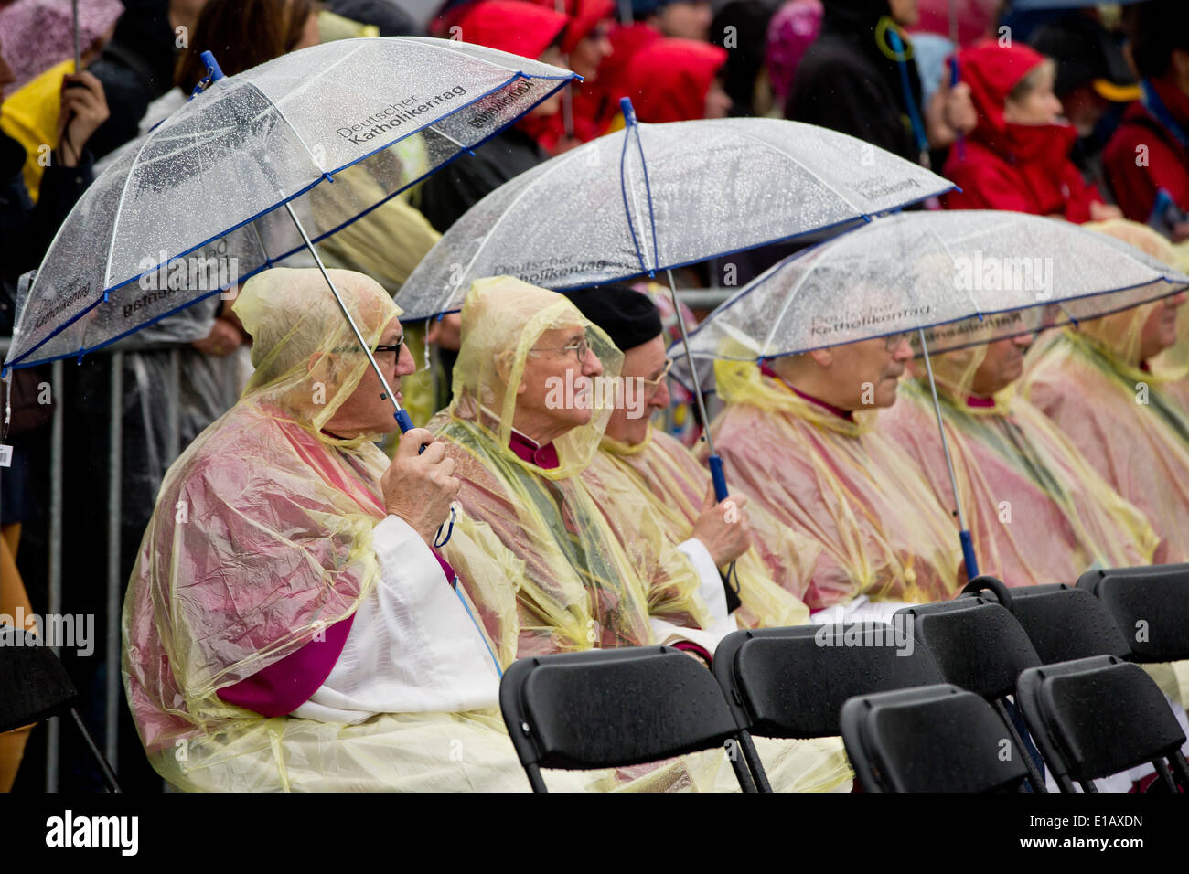 Regensburg, Deutschland. 29. Mai 2014. Mitglieder des Klerus tragen transparente Regenmäntel kauern unter Sonnenschirmen gegen Regenschauer besuchen die Himmelfahrt Masse bei der 99. Deutschen Katholikentag in Regensburg, Deutschland, 29. Mai 2014. Die Veranstaltung dauert bis 01 Juni. Foto: DANIEL KARMANN/Dpa/Alamy Live News Stockfoto