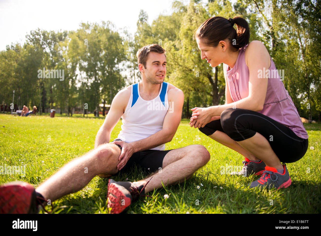 Frau trägt dazu bei, jungen Mann mit verletzten Oberschenkel von sportlichen Aktivitäten Stockfoto