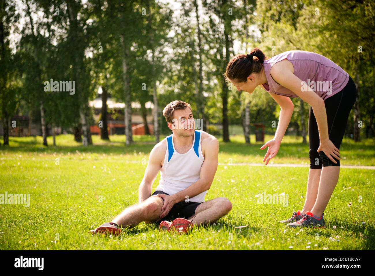 Frau trägt dazu bei, jungen Mann mit verletzten Oberschenkel von sportlichen Aktivitäten Stockfoto