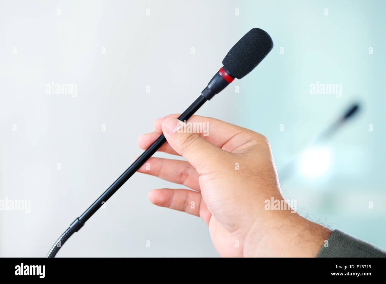 Nahaufnahme von einer Hand hält ein Business-Konferenz-Mikrofon in einem Besprechungsraum Stockfoto