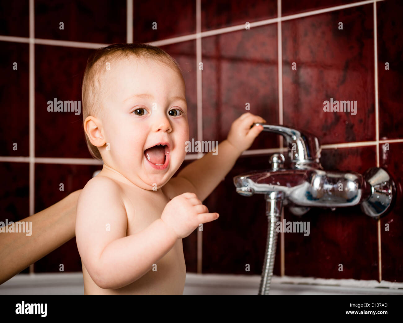 Niedliche Baby Spiel mit Wasserhahn im Badezimmer Stockfoto