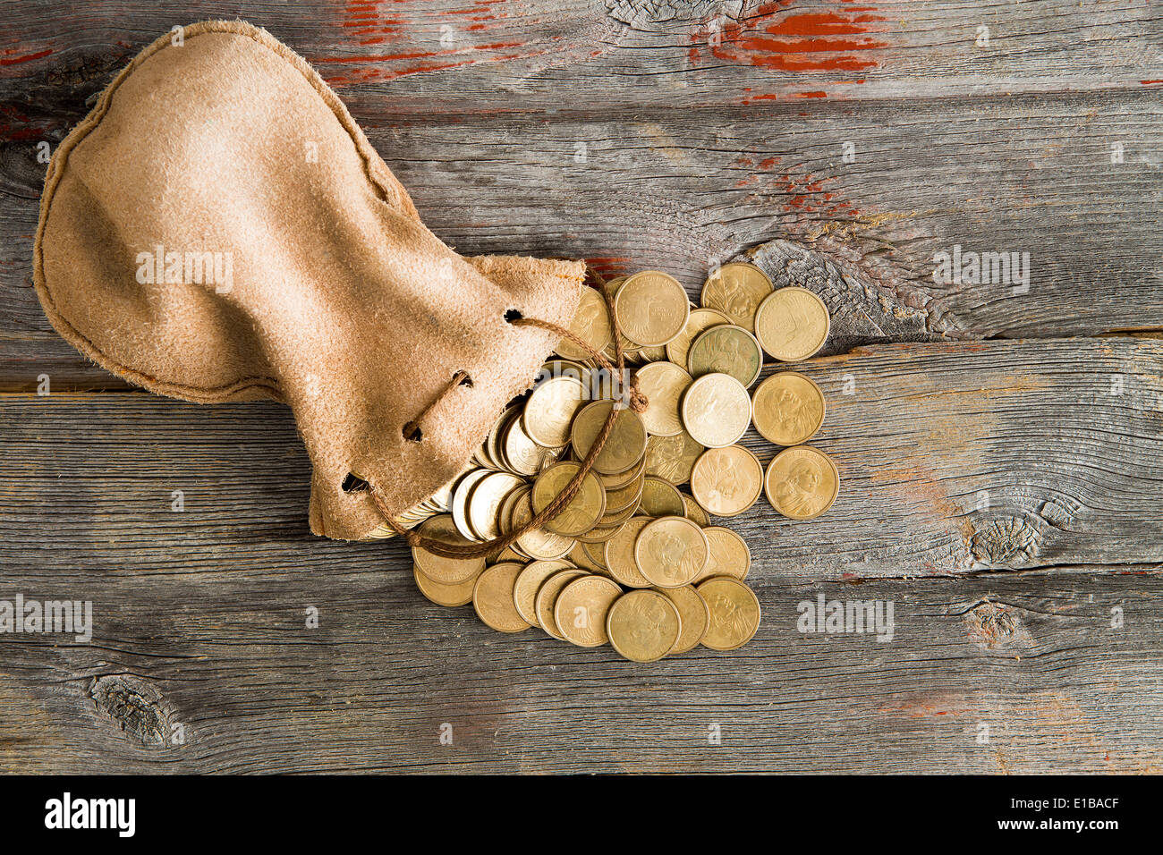 Haufen von Dollar-Münzen aus einem Tunnelzug Beutel auf einem urigen alten verwitterten Holztisch, Ansicht von oben mit Exemplar Stockfoto