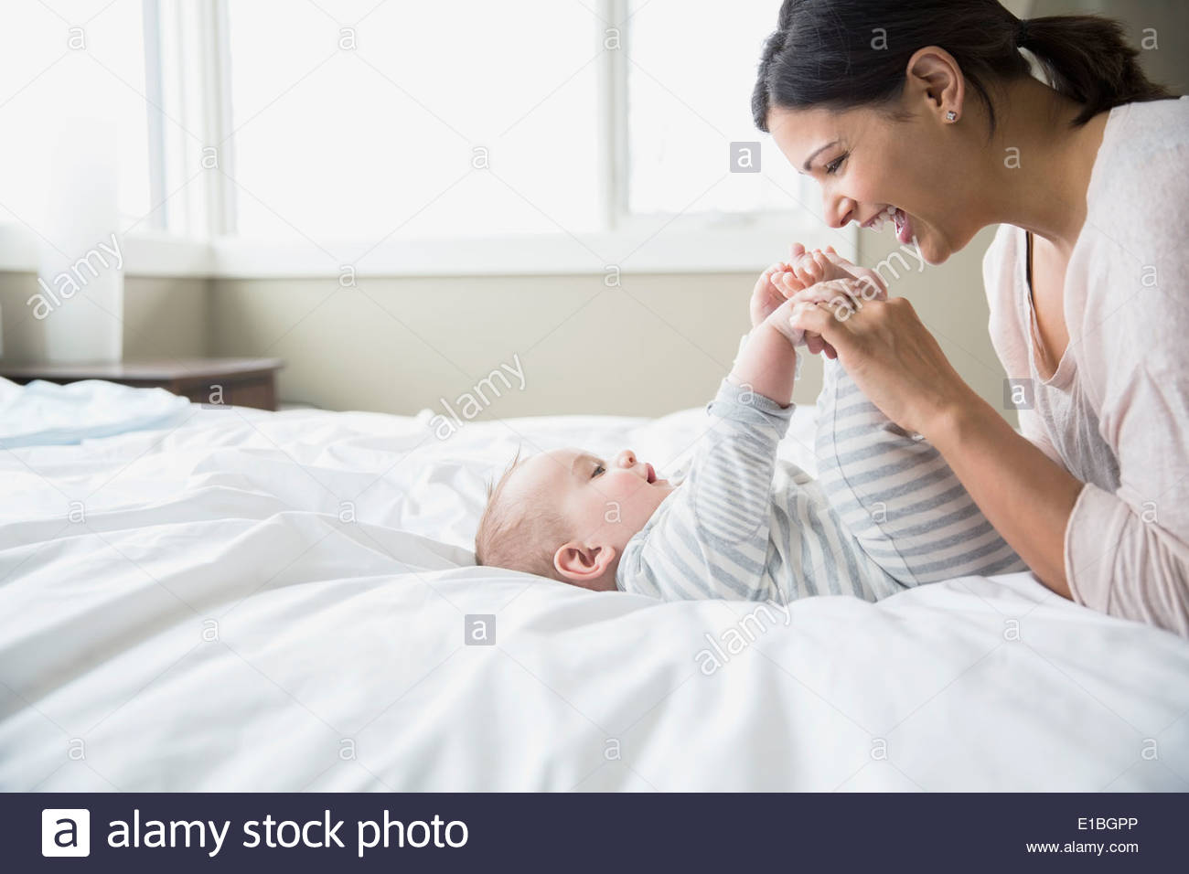 Mutter mit Baby im Bett spielen Stockfoto