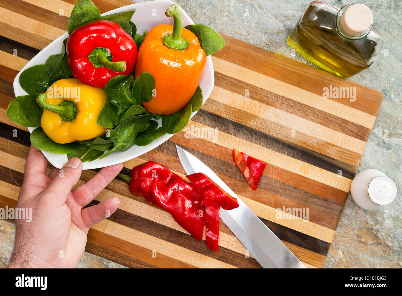 Man bereitet einen gesunden frischen Salat für eine Schale mit bunten süße Paprika in rot, gelb und Orange mit grünen Bab erreichen Stockfoto