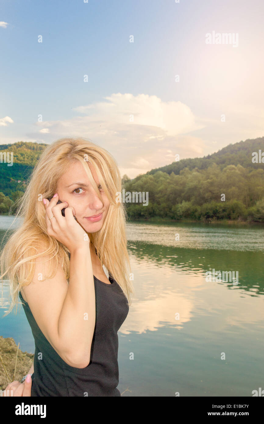 blonde Mädchen am See am Telefon sprechen Stockfoto