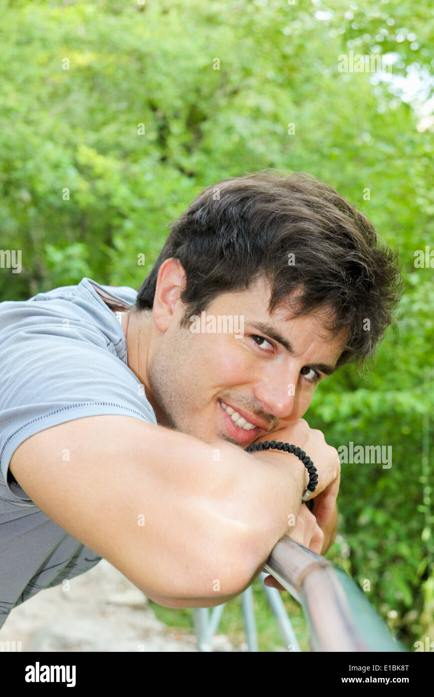 gut aussehender Mann in der Natur lächelnd und stützte sich auf seine hand Stockfoto