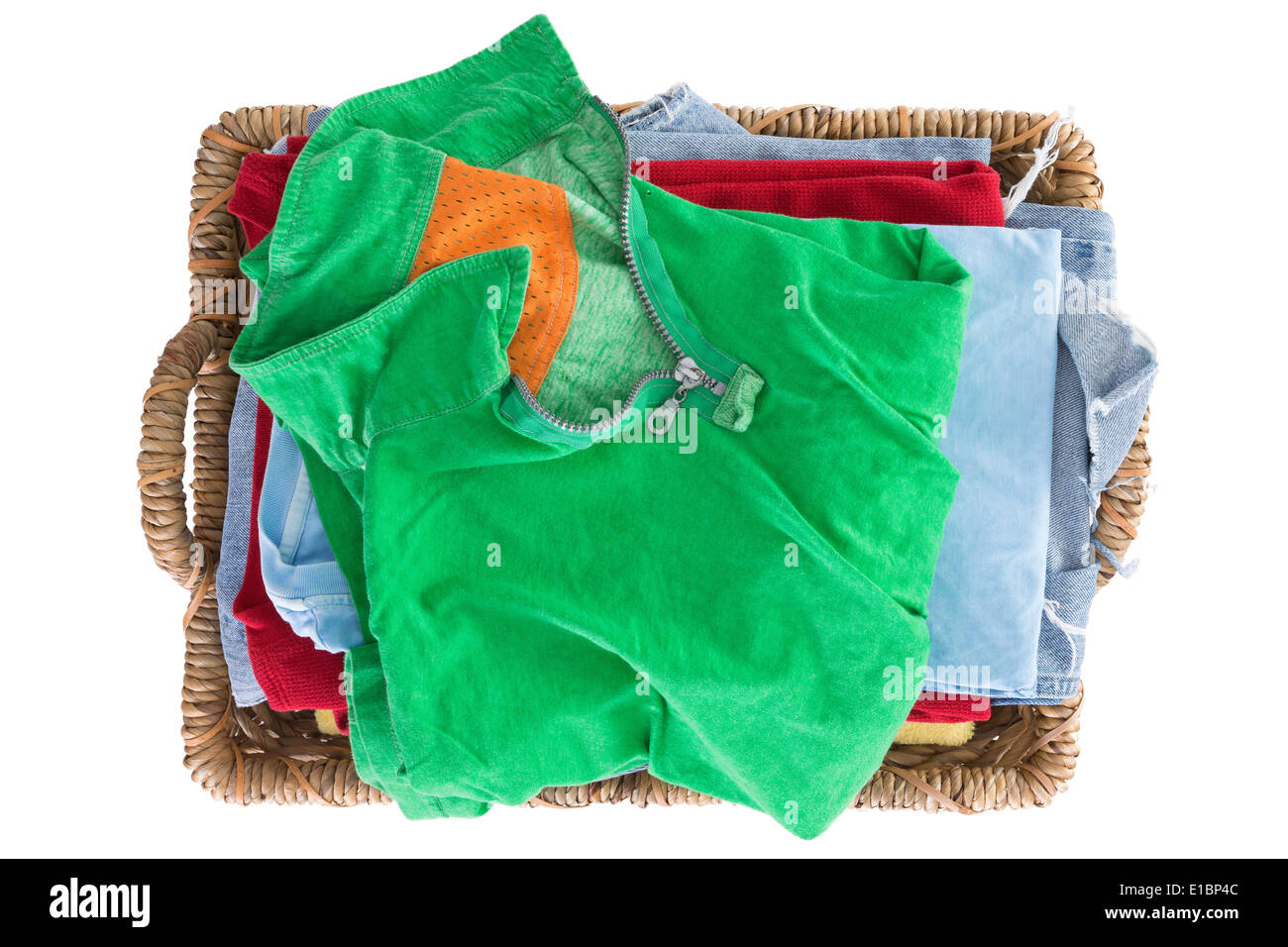 Saubere, frische gewaschene Sommerkleidung in einem Korb ordentlich gefaltet und mit einem bunten grünen Hemd auf den Stapel von oben gesehen Stockfoto