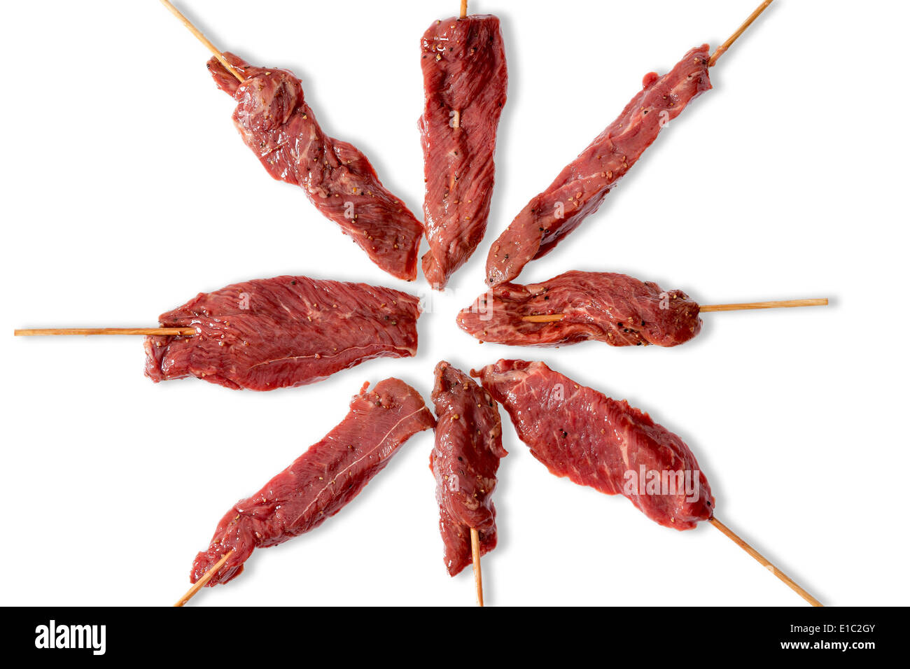 Anordnung der schlanke Ausschreibung roh Rindfleisch Kebab bereit für den Sommer, den Grill auf Stöcken in einem strahlenden Muster auf einem weißen Ba Gewinde Stockfoto