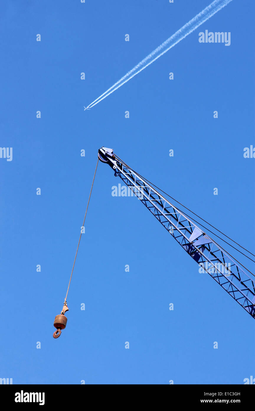 Kran und hoch fliegenden Düsenflugzeug in blauer Himmel Stockfoto