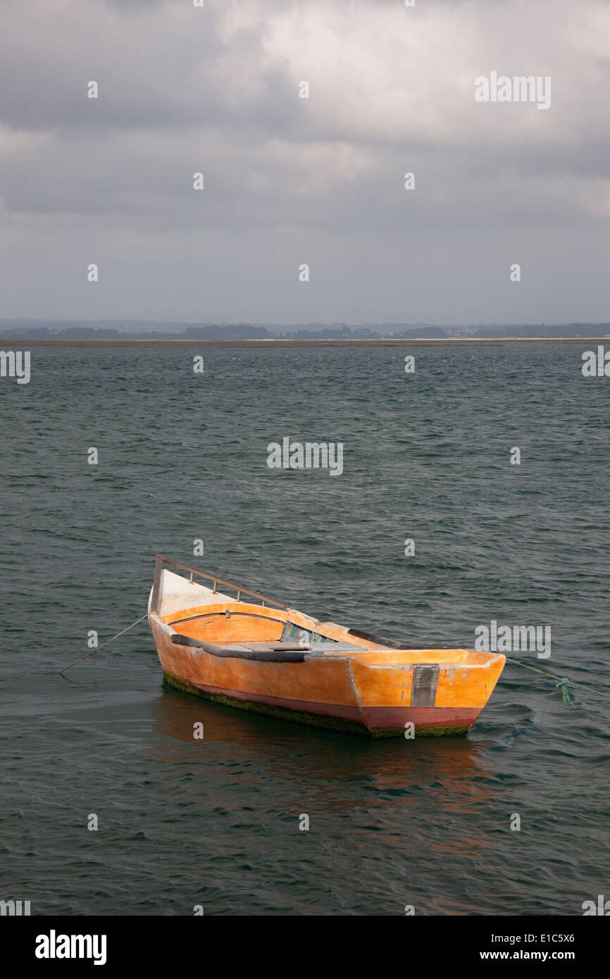 Ein kleines hölzernes Boot vertäut im Freiwasser vor der portugiesischen Küste. Stockfoto