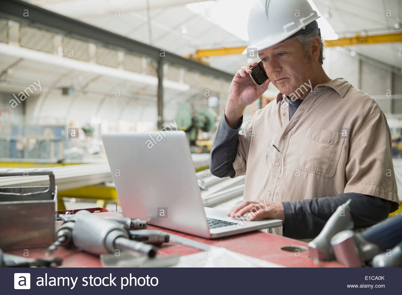 Arbeiter am Laptop im Werksgelände Stockfoto