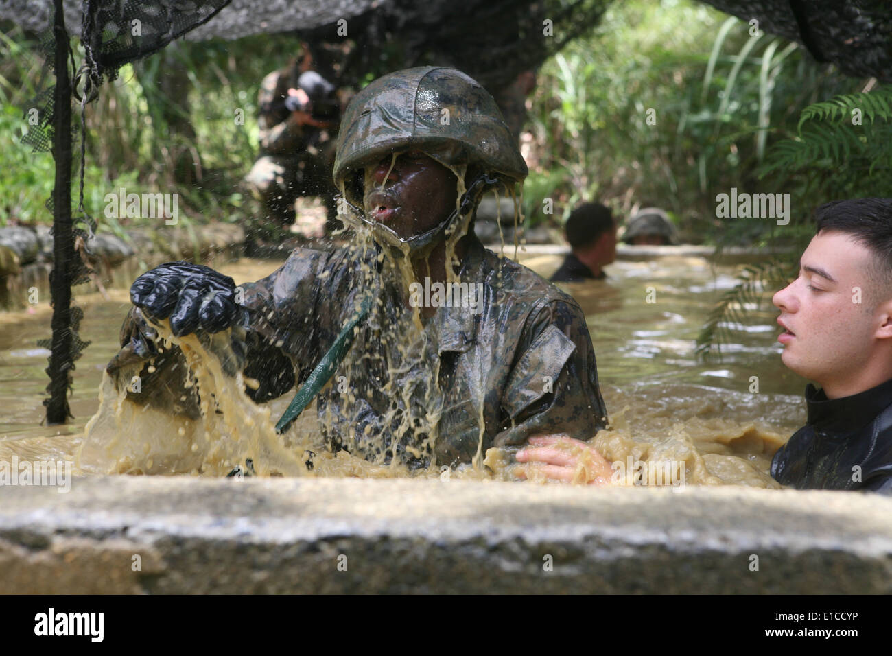 Ein US-Marine spritzt wie er seinen Weg durch ein Hindernis-Parcours in der Jungle Warfare Training Center auf Lager Gonsalves macht, Stockfoto