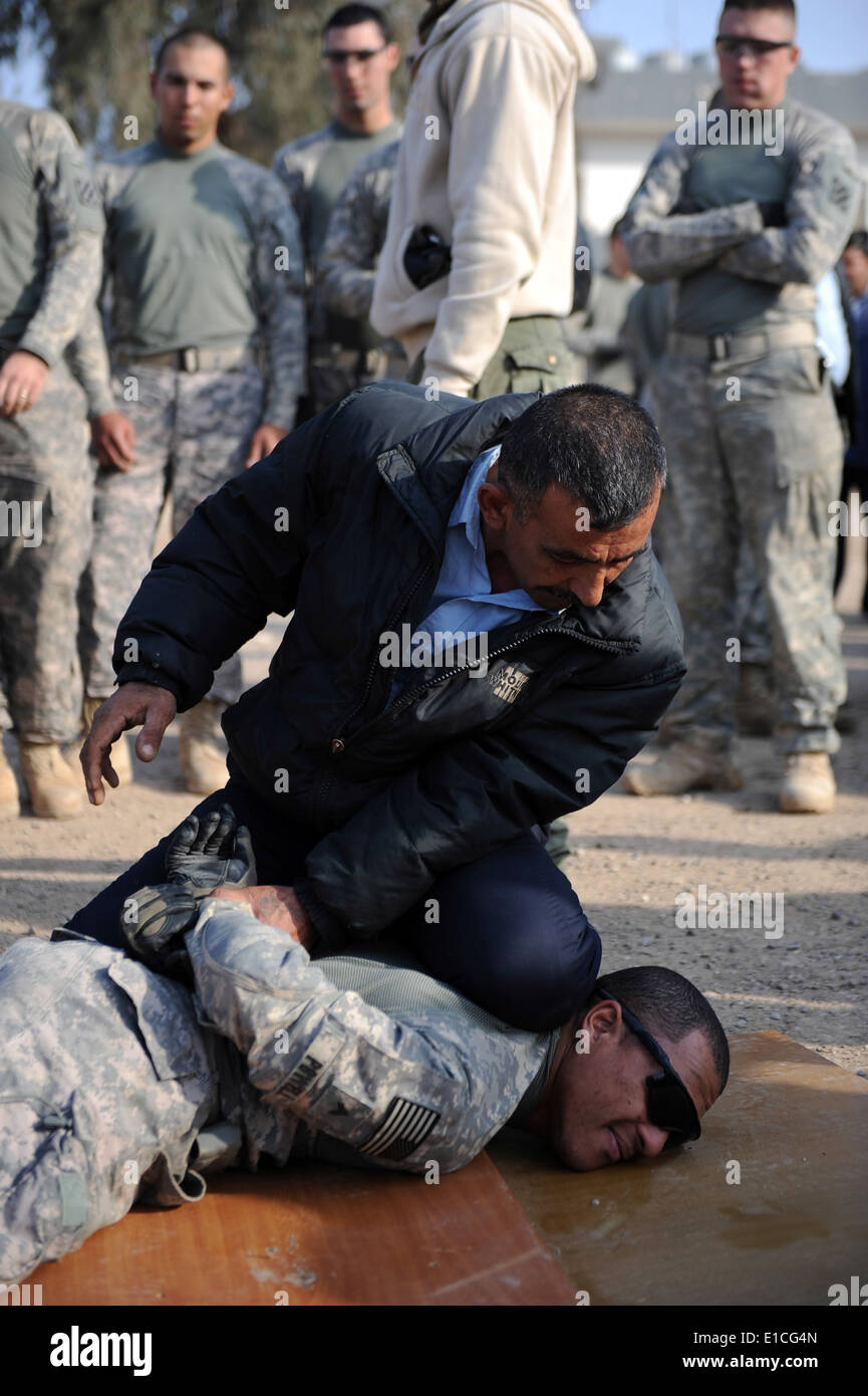 Mitglied einer irakischen Notfallmaßnahmen Unit (ERU) zeigt, dass die Befestigung auf der US-Armee CPL. Antony Powell während Trai-Handschellen Stockfoto