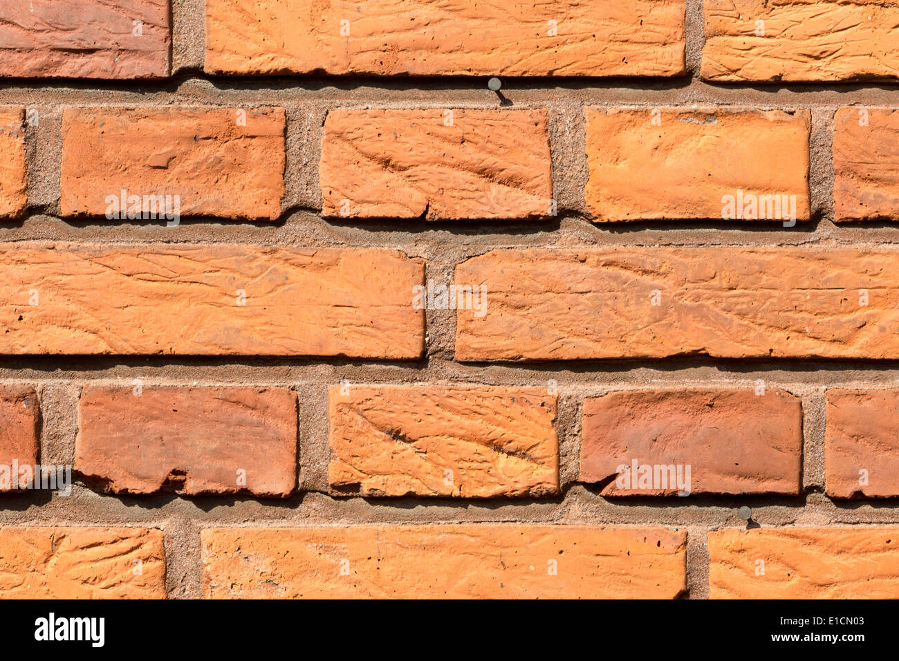 Nahaufnahme der verwitterten roten Backsteinmauer an einem sonnigen Tag. Stockfoto