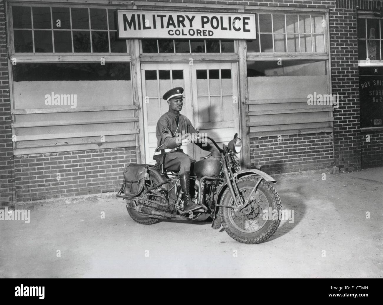Eine afrikanische Amerika MP, Pfc. Victor Tampone, auf seinem Motorrad bereit, Anrufe in seiner Umgebung zu beantworten. Hinter ihm ist ein Zeichen Stockfoto