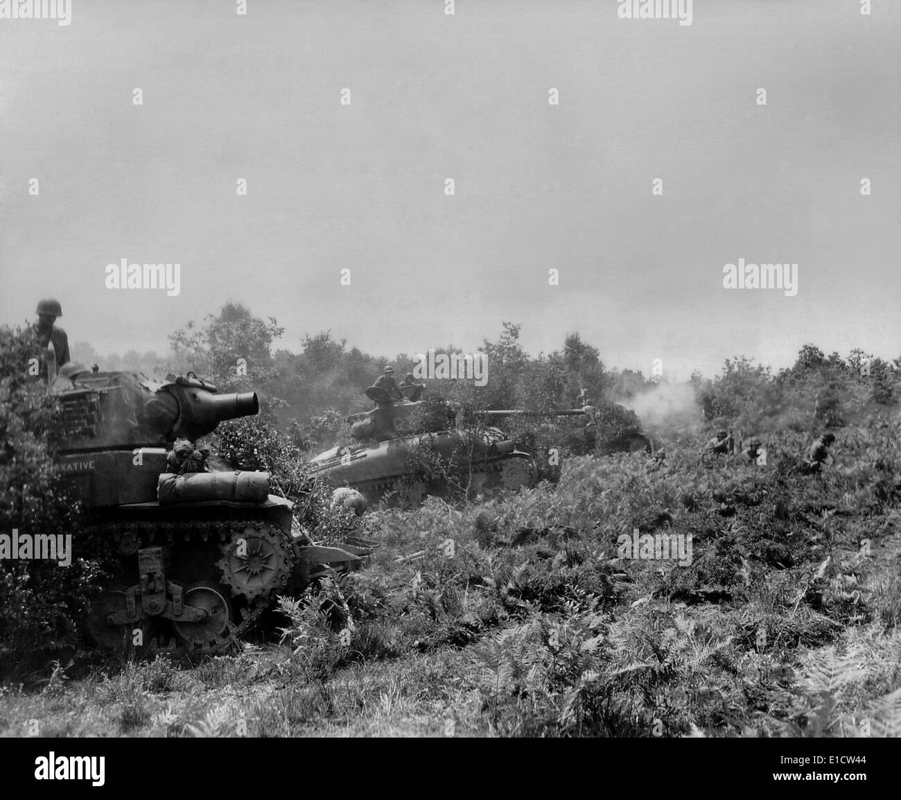 Drei US-Panzer feuern auf deutsche Stellungen in der Schlacht von Falaise Tasche. Drei Soldaten sind auf dem Boden vor der Stockfoto