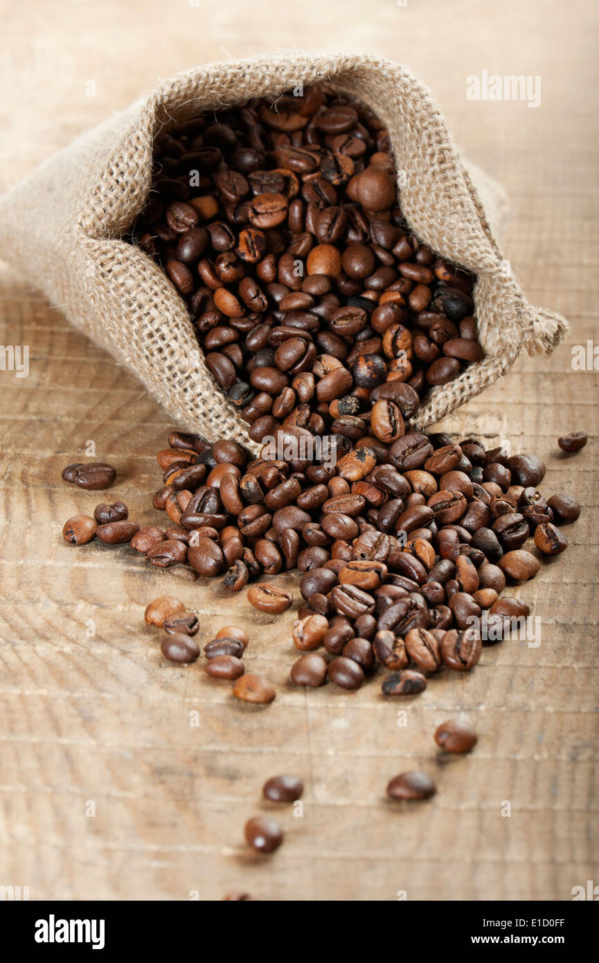 Jute-Tasche mit Kaffeebohnen auf Holztisch Stockfoto