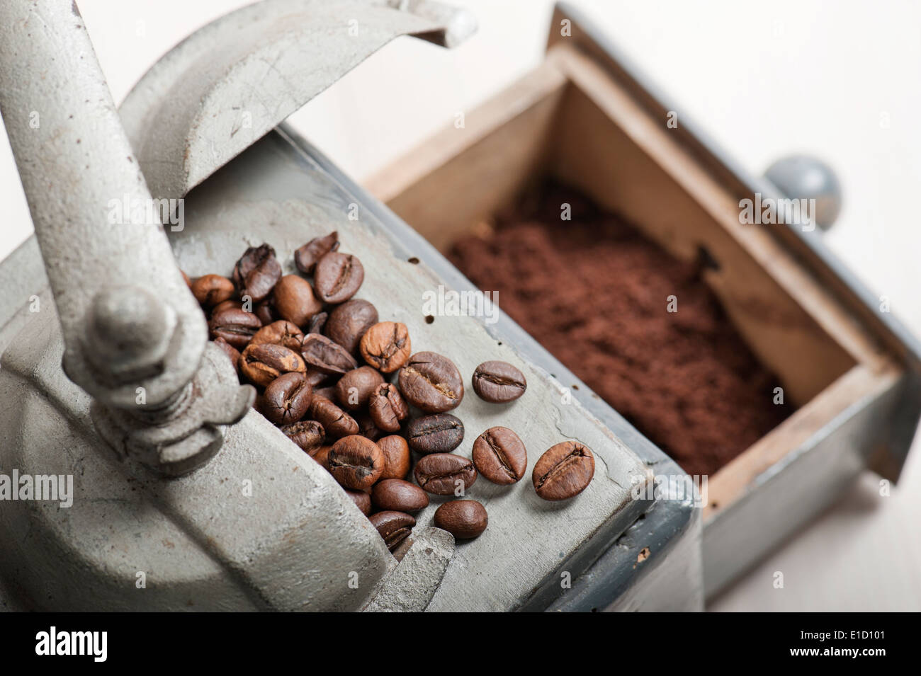 alte Kaffeemühle mit Kaffeebohnen und Kaffeesatz auf Holztisch Stockfoto