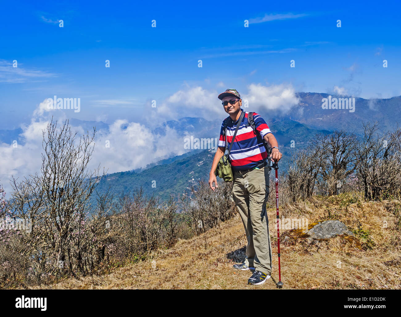 Ein Trekker Reisender auf einem Hügel beim trekking durch die Berge des Himalaya mit Gehstock, Wolke, Himmel, Büsche mit Textfreiraum Stockfoto