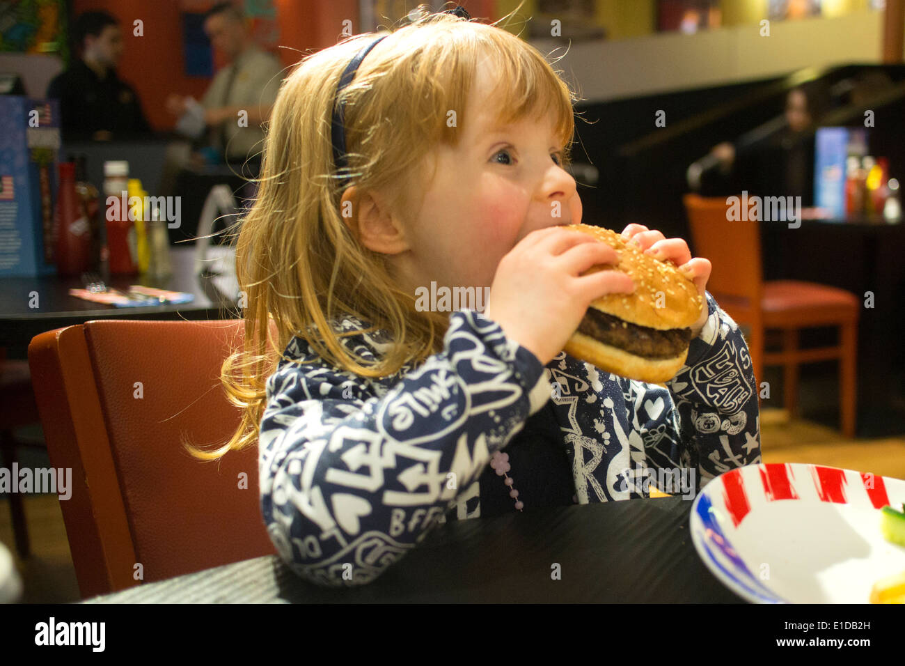 Vier 4 Jahre altes Mädchen im Restaurant essen Käse burger Stockfoto