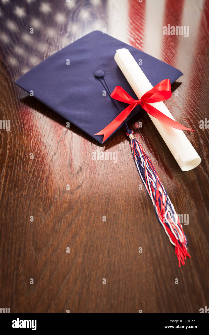 Graduation Cap mit Quaste und Schüler abzuringen auf Holztisch mit amerikanische Flagge Reflexion. Stockfoto