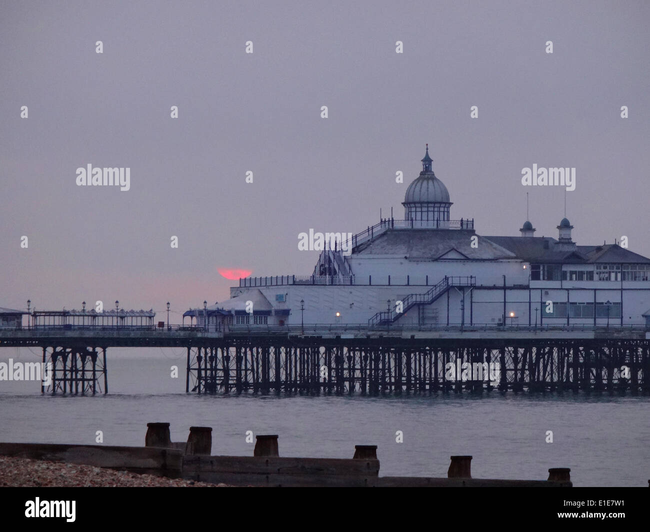 Eastbourne, East Sussex, Großbritannien. Juni 2014. Sehr kurzer Blick auf die Sonne, wenn sie in einen niedrigen Coud hinter dem Pier steigt. Nach einigen Prognosen soll das Wetter in den nächsten vierzehn Tagen feuchter werden Stockfoto