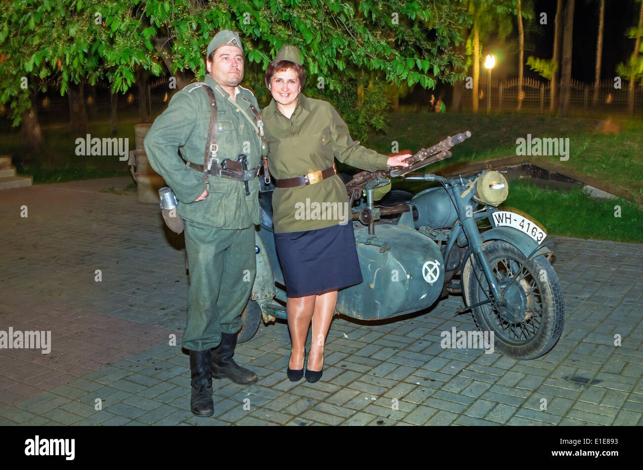 Schauspieler aus militärischen Museumsverein und Gast in der Nähe von Motorrad auf einer Ausstellung des Museums. Nacht im Museum-Gebiet. Stockfoto