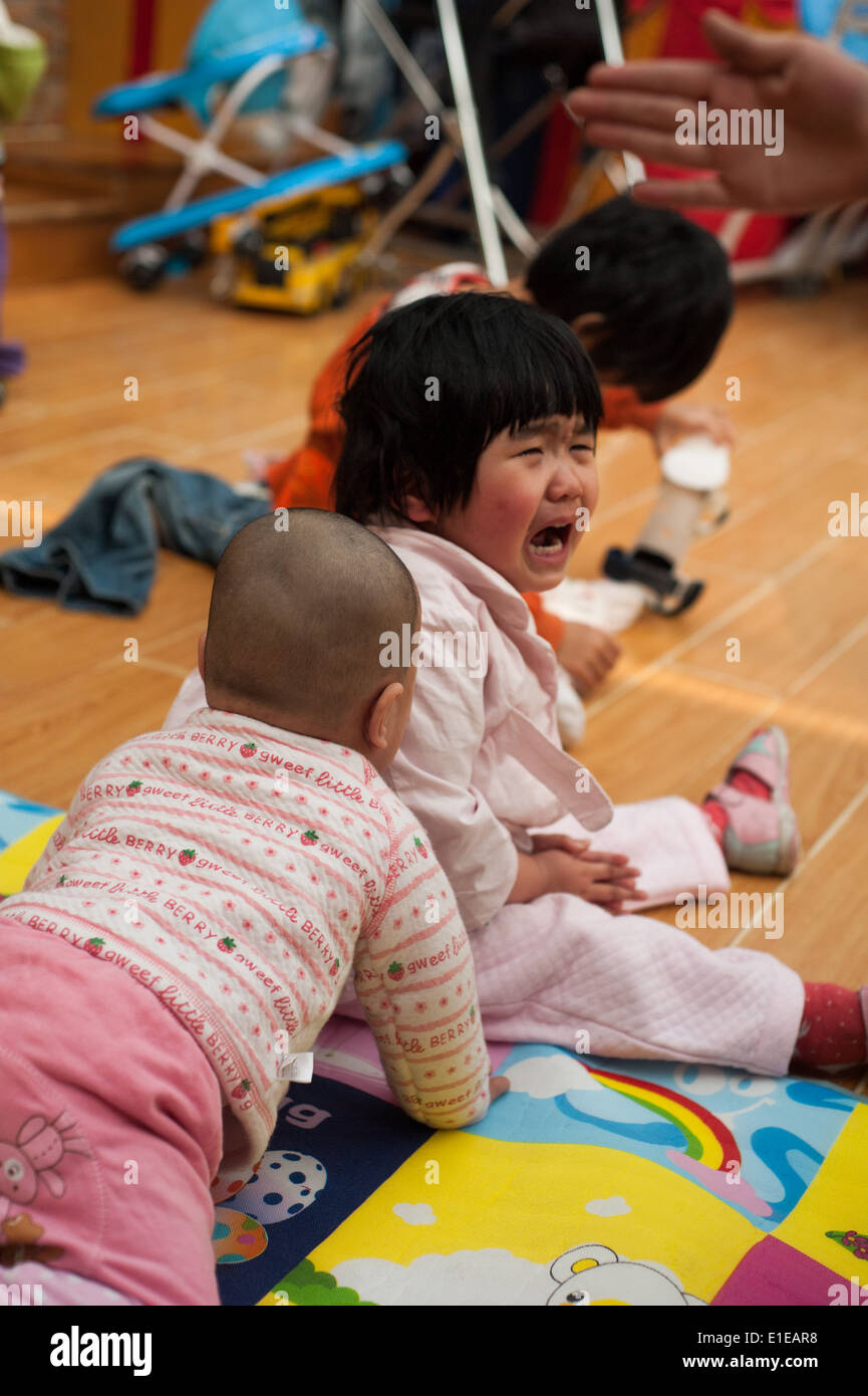 Kind weint beim Sitzen auf dem Boden oder an ein Waisenhaus in Peking Stockfoto