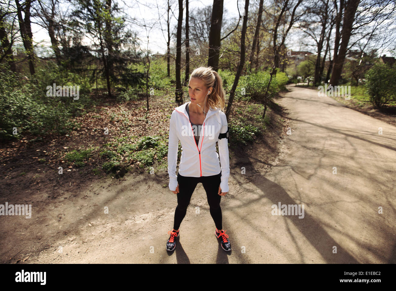 Junge Frau in Ausübung Kleidung stehend auf einem Waldweg wegsehen. Fitness Frauen auf im freien Trainings. Stockfoto