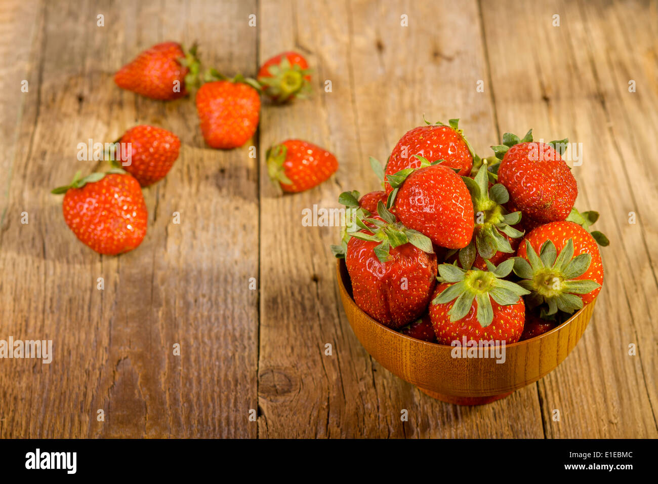 frische Erdbeeren in Holz Schüssel auf alten hölzernen Hintergrund Stockfoto