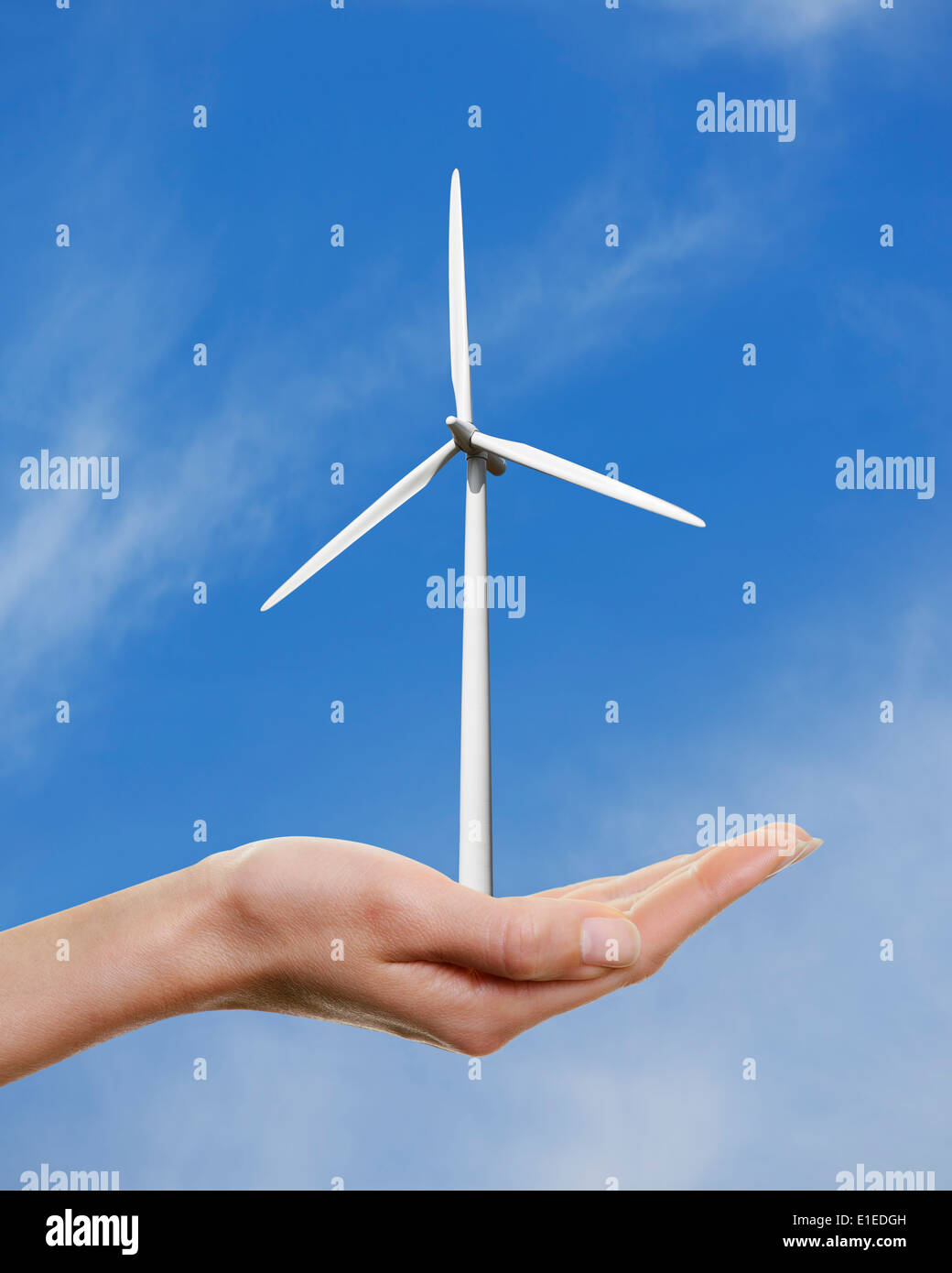 Womans Hand hält eine Windkraftanlage vor blauem Himmel. Stockfoto